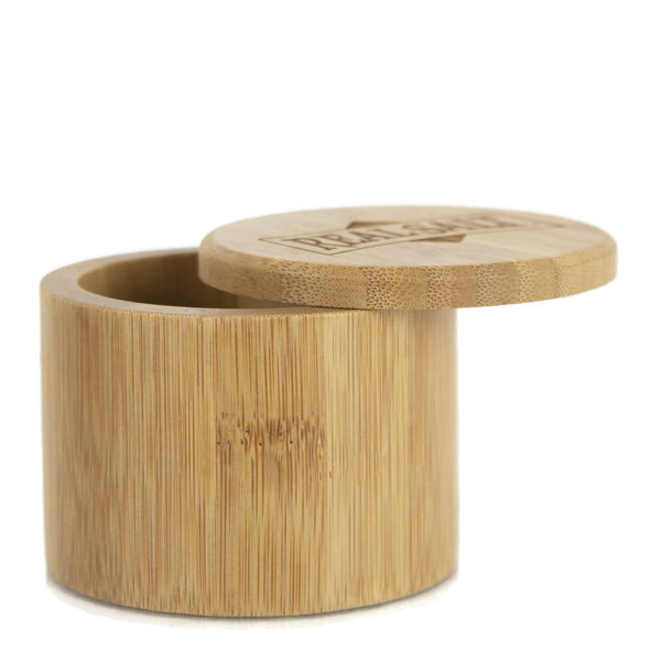 Open bamboo storage jar with engraved lid resting on side. 
