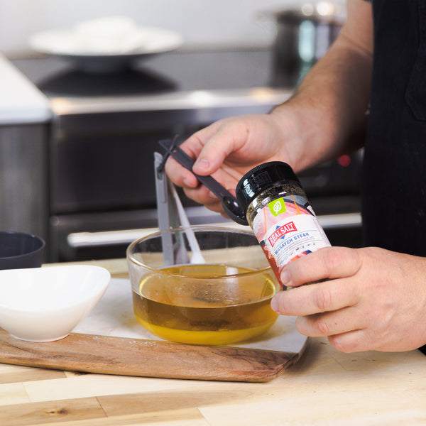 Chef measures Real Salt Wasatch Steak seasoning into a glass bowl of melted butter. 
